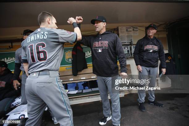 Chris Owings and Manager Torey Lovullo of the Arizona Diamondbacks bump fist in the dugout prior to the game against the Oakland Athletics at the...