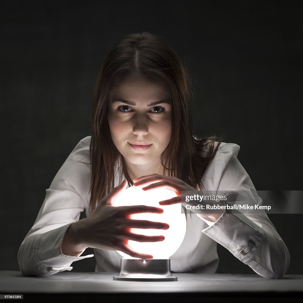 Studio portrait of young woman holding crystal ball