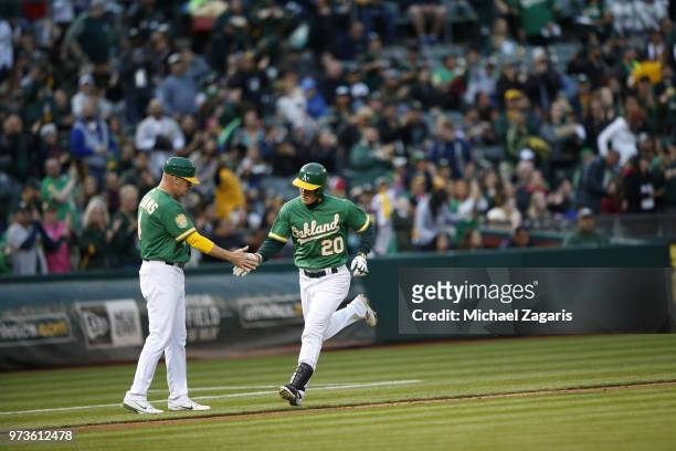 Mark Canha of the Oakland Athletics is congratulated by Third Base Coach Matt Williams while running the bases after hitting a home run during the...