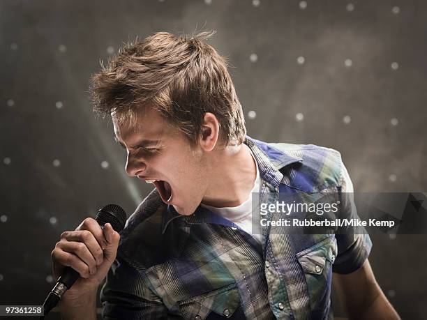 young man singing, studio shot - microphone mouth stock pictures, royalty-free photos & images