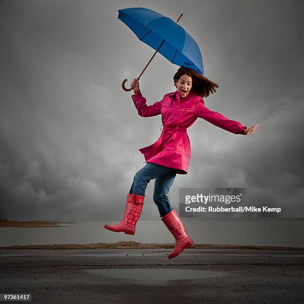 usa, utah, orem, woman with umbrella jumping under overcast sky - pardessus photos et images de collection
