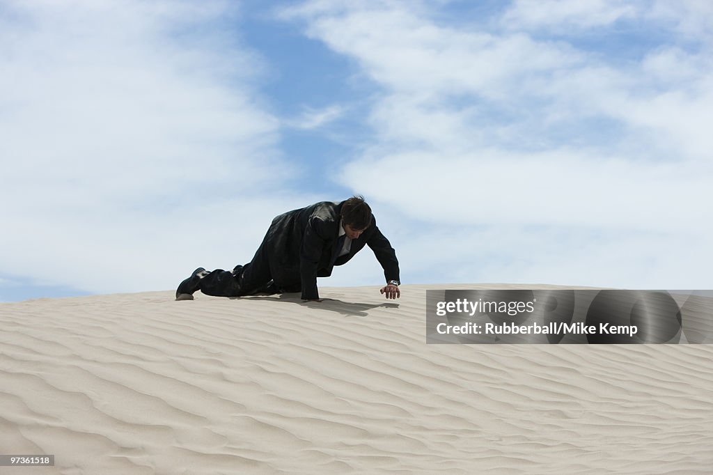 USA, Utah, Little Sahara, mid adult businessman crawling over sand dune