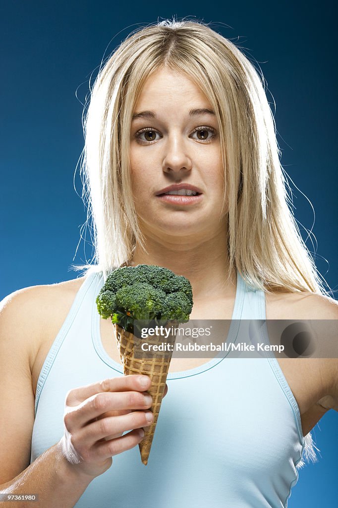 Studio portrait of young woman holding broccoli ice cream