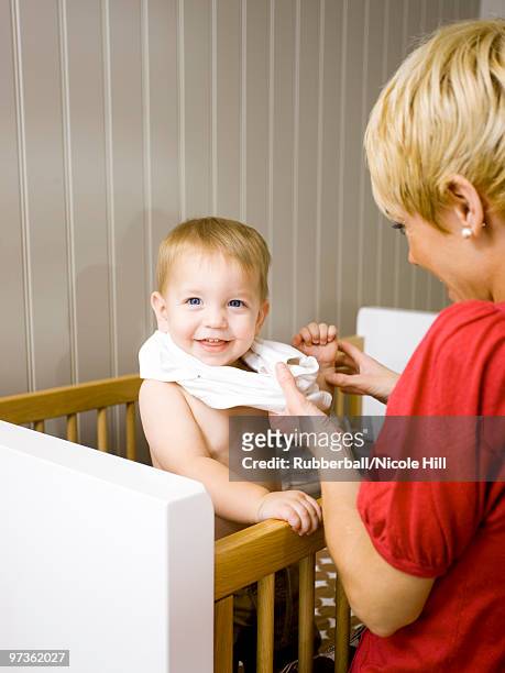 usa, utah, provo, mother dressing baby boy (18-23 months) in crib - 18 23 months stock pictures, royalty-free photos & images