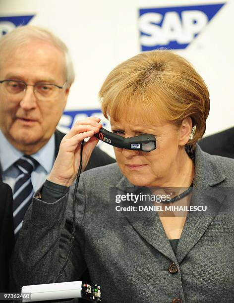 German Chancellor Angela Merkel inspects a "Head-Mounted Display" made by German software giant SAP next to German Economy Minister Rainer Bruederle...