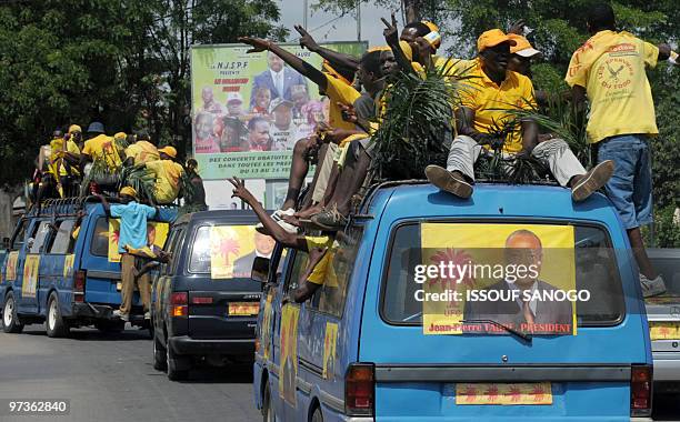 Supporters of Togo's main opposition Union for the change candidate Jean-Pirre Fabre drive past a poster of Togo�s outgoing president Faure...