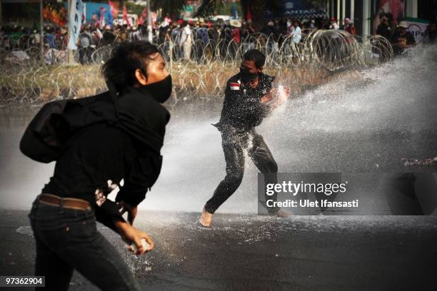 Police hose protesters with a water cannon as they demonstrate outside the House of Representatives' inquiry into the Bank Century bailout at...