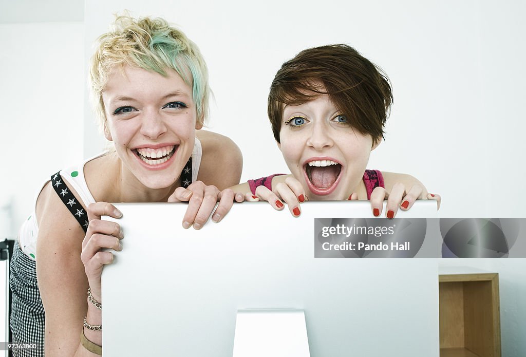 Two girls looking over computer, laughing