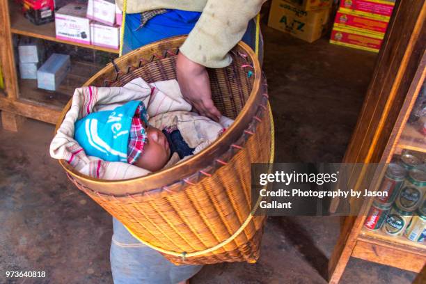 baby being carried in a basket in loikaw, myanmar. - loikaw fotografías e imágenes de stock