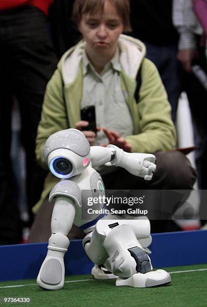 Visitor watches a robot pull itself up after falling while playing football in a demonstration of artificial intelligence at the stand of the German...