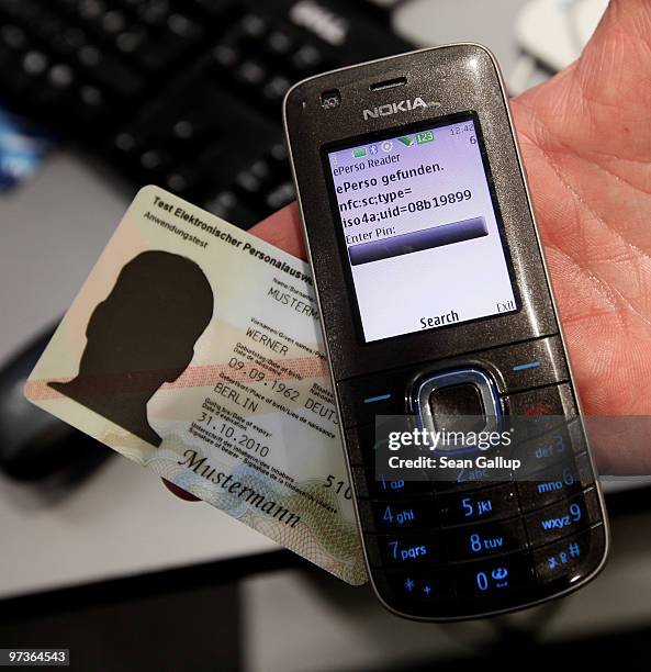 Host displays a sample new German national identity card with its data transmitted to a mobile phone at the Fraunhofer Institute stand at the CeBIT...