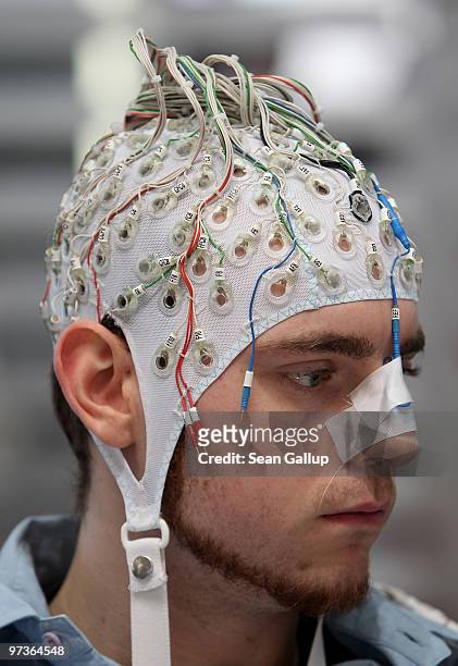 Man, wearing an EEG brain scanning apparatus on his head, plays a pinball game solely through willing the paddles to react with his brain at the...