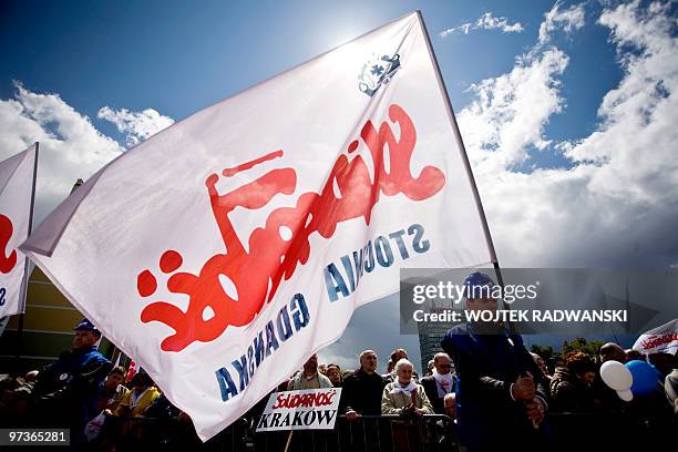 Shipyard worker holds aloft a Solidarity trade union flag in front of the Shipyard Workers Monument during celebrations of 20th anniversary of first...