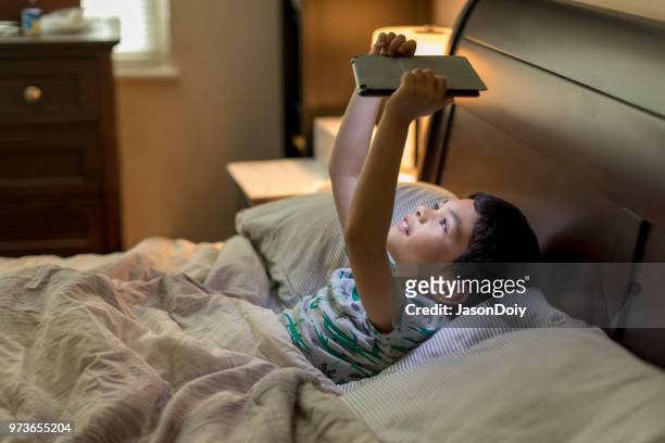 boy with tablet computer in bed - jasondoiy imagens e fotografias de stock