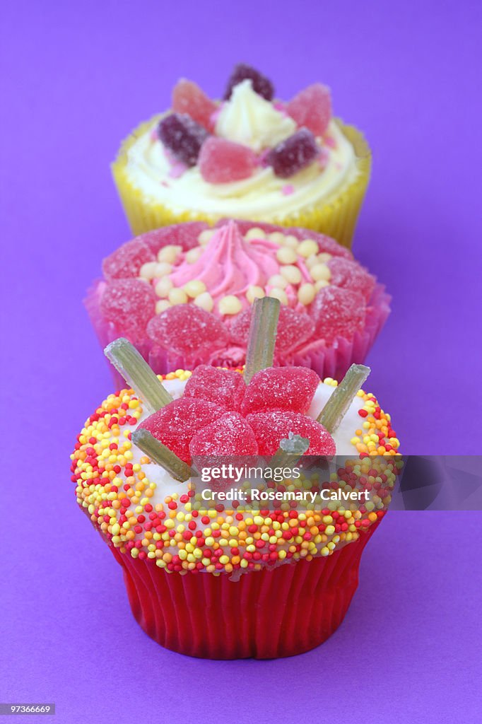 Brightly colored cupcakes on purple background.