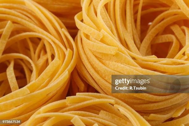 dried italian pasta, fettuccine nests, abstract food background, closeup shot - フェットチーネ ストックフォトと画像