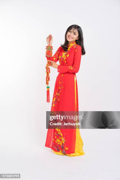young woman wearing vietnamese red color ao dai, smiling, holding lucky object for new year - jethuynh stock pictures, royalty-free photos & images