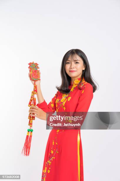 young woman wearing vietnamese red color ao dai, smiling, holding lucky object for new year - jethuynh stock pictures, royalty-free photos & images