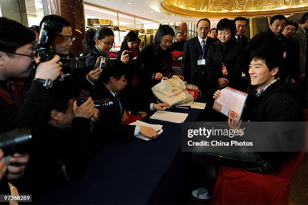 Olympic hurdle champion Liu Xiang answers questions from the media as he arrives at a hotel to attend the annual session of the 11th National...