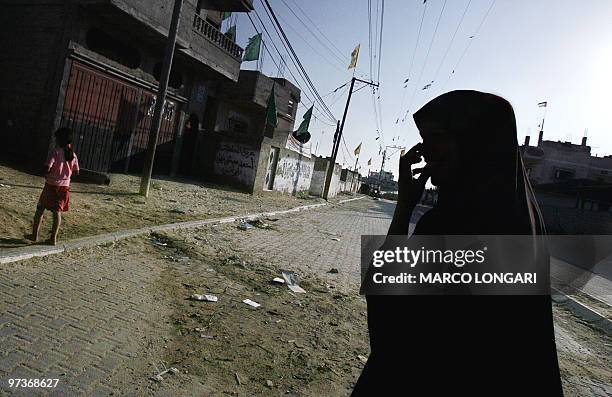 Palestinian woman crosses the road with her doughter in a deserted street 22 August 2005 in the Baten El-Sameen district of Khan Yunes, Gaza Strip,...