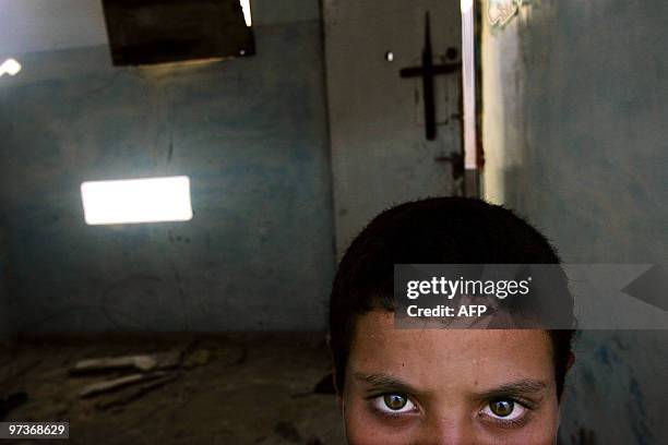 Palestinian Ahmed Etah poses inside a destroyed house 21 August 2005, in the refugee camp of Khan Yunes, Gaza Strip, close the wall that separates...