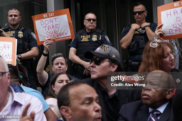 Department of Homeland Security police officers watch demonstrators outside the headquarters of U.S. Customs and Border Protection during a protest...