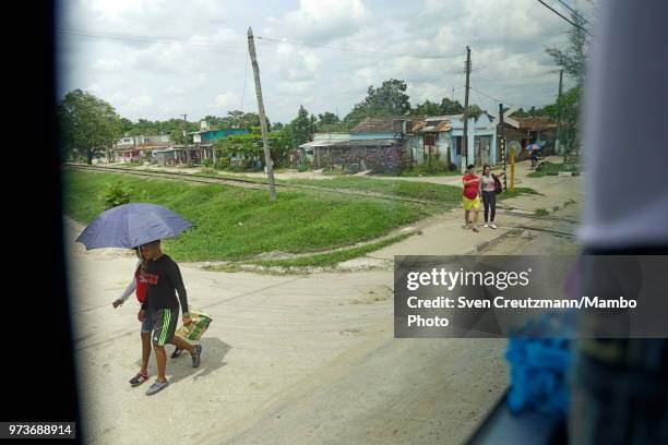 Cubans walk next to a Chinese Yutong bus as it crosses railway tracks, on June 11, 2018 in Ciego de Avila, Cuba. Busses have turned even more...