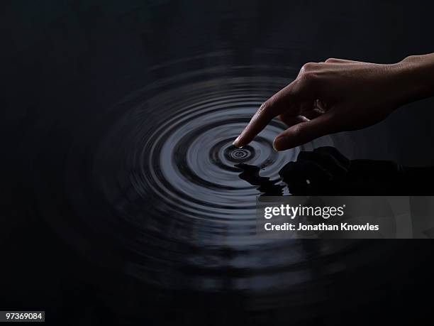 finger creating ripples - murky water ストックフォトと画像