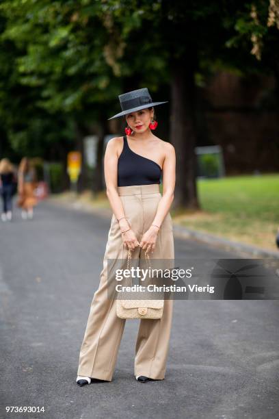 Guest wearing black body, beige high waisted pants, Chanel bag and shoes, hat, red earrings is seen during the 94th Pitti Immagine Uomo on June 13,...