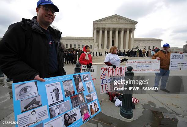 Demonstrators display placards supporting a case on bearing arms in the District of Columbia area, in front of the Supreme Court in Washington, DC,...