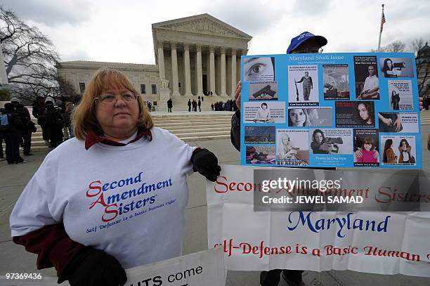 Demonstrators display placards supporting a case on bearing arms in the District of Columbia area, in front of the Supreme Court in Washington, DC,...