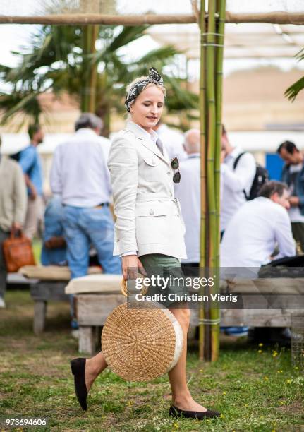 Monika Kaminska wearing round straw bag, beige belted safari linen jacket with patched pockets, button down shirt, green bermuda shorts is seen...