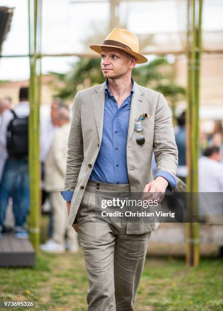 Roman Zaczkiewicz wearing khaki sarfari linen suit Zack Roman, chambray button down shirt, cuffed two pleats linen trousers, panama hat, blue button...