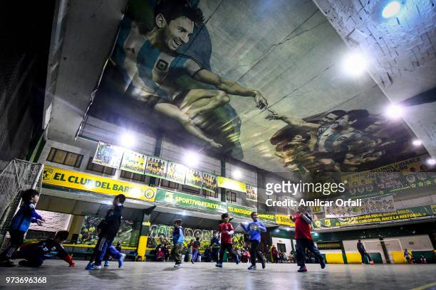 Young players run suring a soccer match at Sportivo Pereyra de Barracas Club on June 13, 2018 in Buenos Aires, Argentina. The mural was painted in...