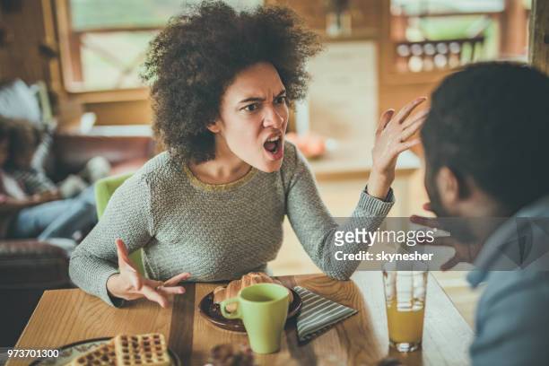 angry african american woman arguing with her husband at dining table. - angry black woman stock pictures, royalty-free photos & images