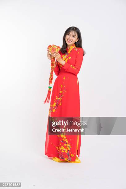 young woman wearing vietnamese red color ao dai, smiling, holding a lucky firecracker for new year to wish lucky and rich. - jethuynh stock pictures, royalty-free photos & images