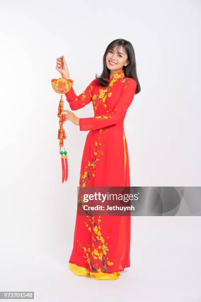 young woman wearing vietnamese red color ao dai, smiling, holding a lucky firecracker for new year to wish lucky and rich. - jethuynh stock pictures, royalty-free photos & images