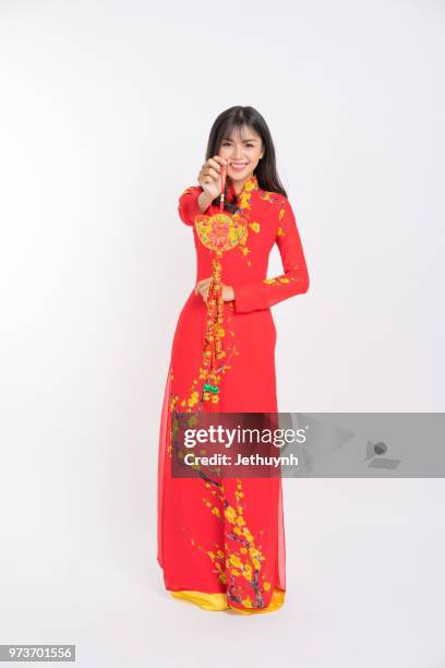 young woman wearing vietnamese red color ao dai, smiling, holding a lucky firecracker for new year to wish lucky and rich. - jethuynh stock pictures, royalty-free photos & images