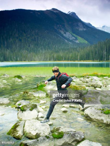 man leaping over mountain stream - john p kelly stock pictures, royalty-free photos & images