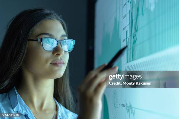 businesswoman studying graphs on an interactive screen in business meeting - inteligencia empresarial fotografías e imágenes de stock