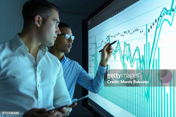 businessmen studying graphs on an interactive screen in business meeting - scrutiny stock pictures, royalty-free photos & images