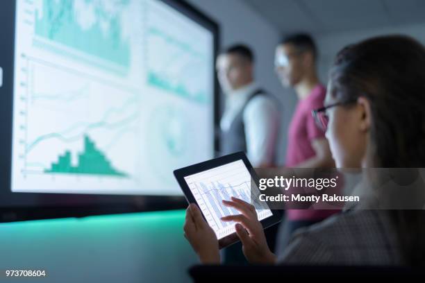 businesswoman viewing graphs on digital tablet in business meeting - business analytics stockfoto's en -beelden