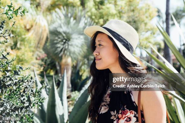 young woman outdoors, looking at plants in garden - teich stock pictures, royalty-free photos & images