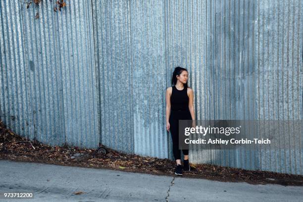 portrait of young woman standing in front of corrugated fencing - teich stock pictures, royalty-free photos & images