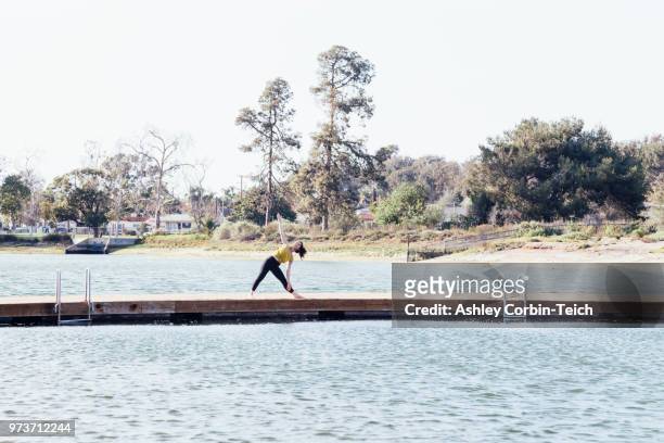 young woman outdoors, on pier, in yoga position, long beach, california, usa - teich stock pictures, royalty-free photos & images