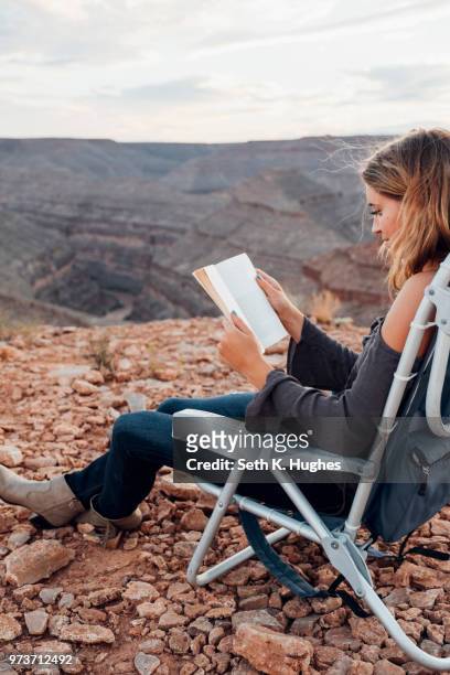 young woman in remote setting, sitting on camping chair, reading book, mexican hat, utah, usa - mexican hat fotografías e imágenes de stock