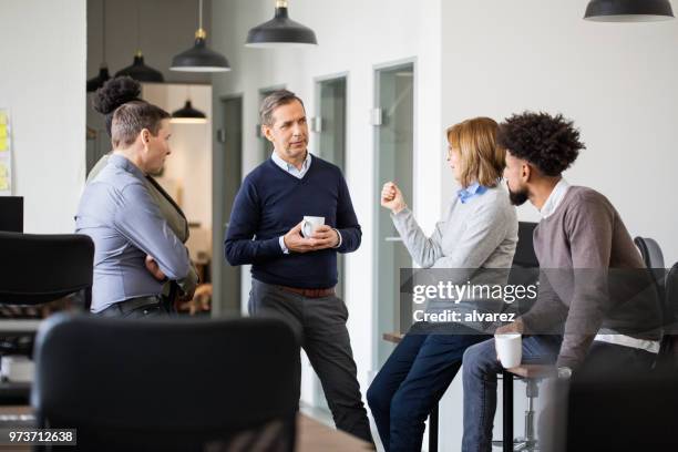 colleagues having a casual talk during coffee break - office coffee break stock pictures, royalty-free photos & images