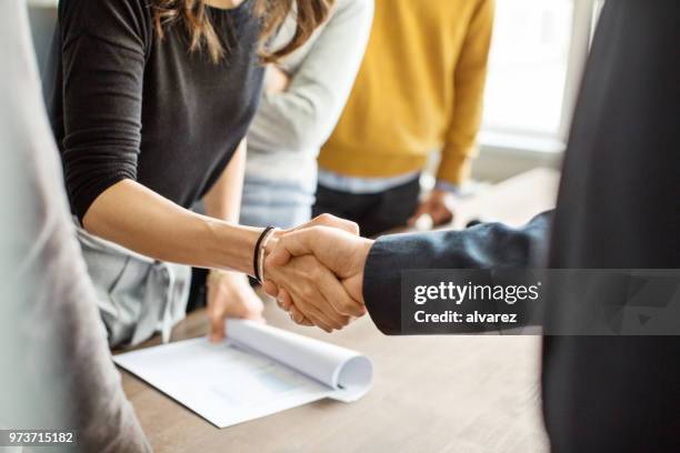 geschäftsleuten beim händeschütteln im büro - handshake stock-fotos und bilder