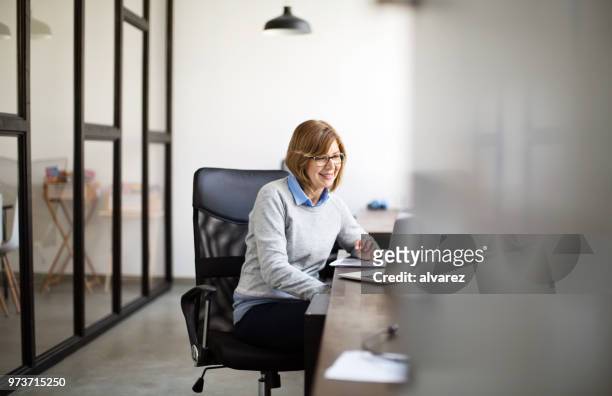 senior woman working at her office desk - cubicle work stock pictures, royalty-free photos & images
