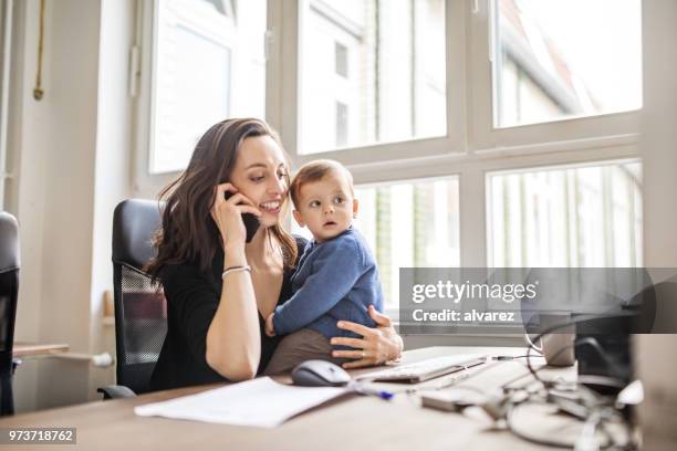 alleinerziehende mutter mit sohn arbeiten im büro - multitasking stock-fotos und bilder